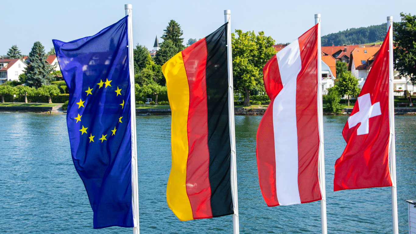 Die Flaggen der EU, Deutschlands, Österreichs und der Schweiz mit dem Bodensee im Hintergrund